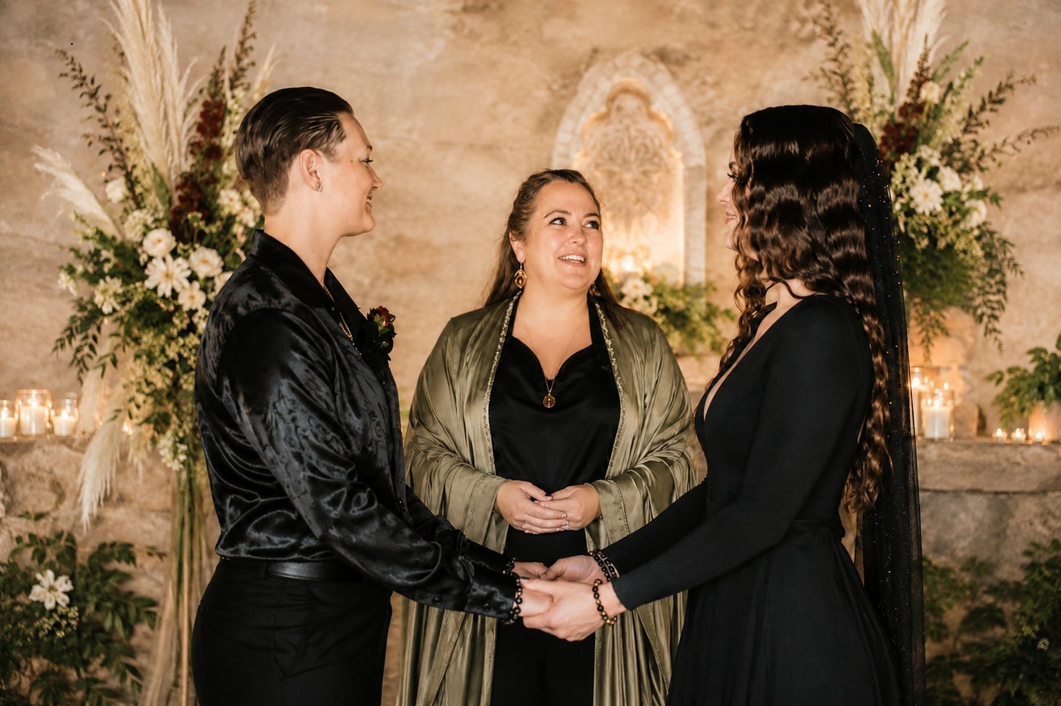 Sarah officiating a wedding ceremony as a couple holds hands in a warm ceremonial space
