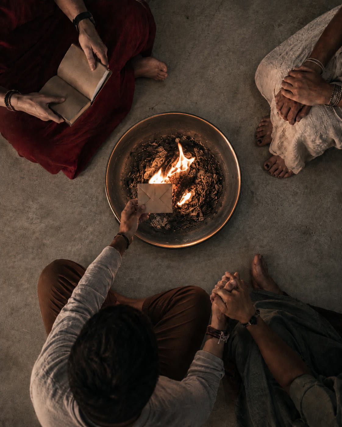A release and reclamation ceremony with hands, a fire bowl, and an envelope